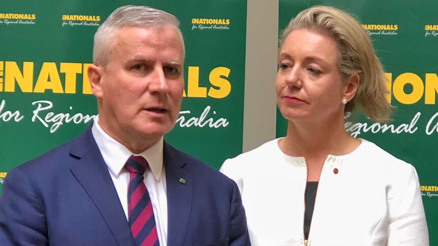 Michael McCormack speaks at a microphone while Bridget McKenzie looks on.