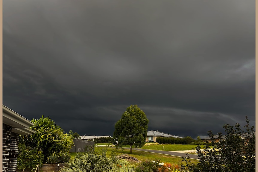 dark ominous clouds over houses in the suburb of beechwood as a storm from approaches 