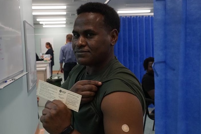 A man shows his vaccination certificate and bandaid on his arm after receiving his coronavirus jab.