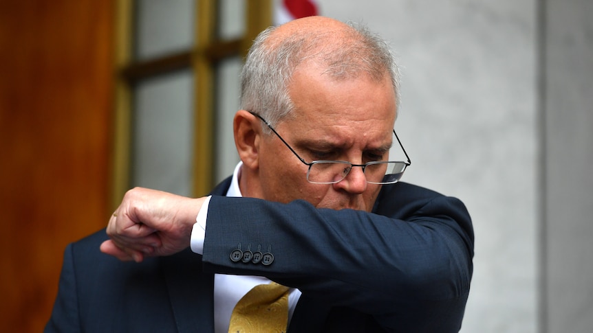 Scott Morrison coughs into his elbow during a press conference at parliament house