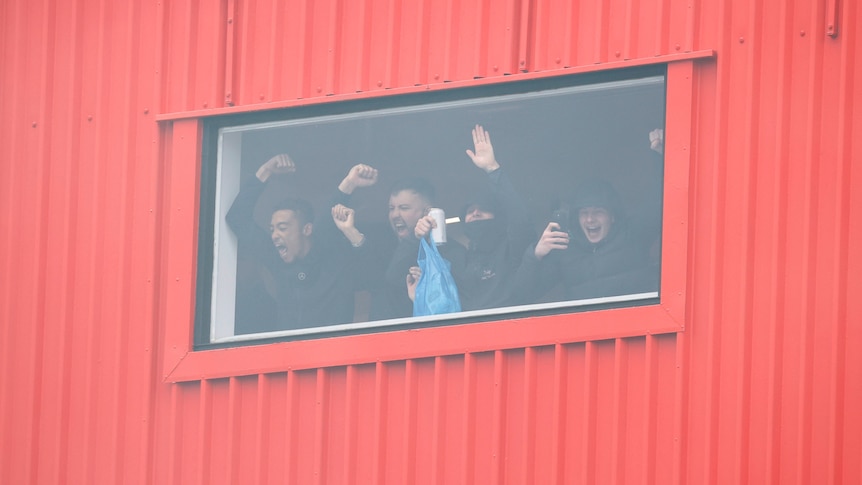 Manchester United fans inside Old Trafford cheering from the window
