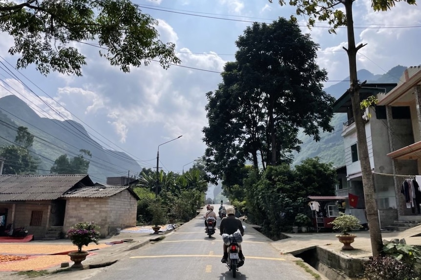 A motorcycle tour group rides through a small Vietnam village on the Ha Giang loop.