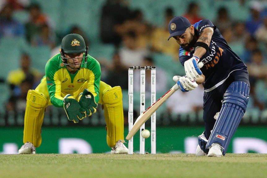 India's Virat Kohli concentrates as he hits a cover drive with Australia's Alex Carey behind the stumps looking on