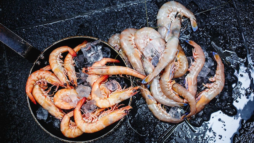 Pans of tiger and king prawns on a barbecue