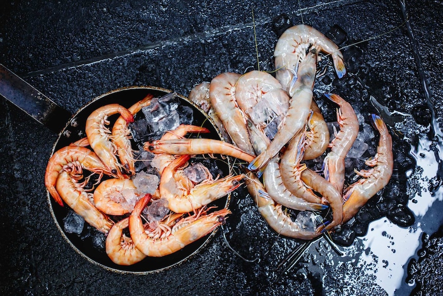 Pans of tiger and king prawns on a barbecue