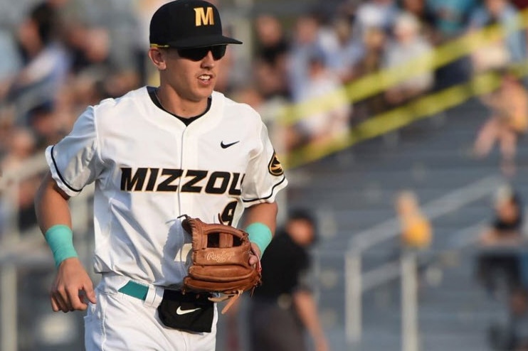 University of Missouri baseball player Robbie Glendinning jogs in the field wearing a white uniform.