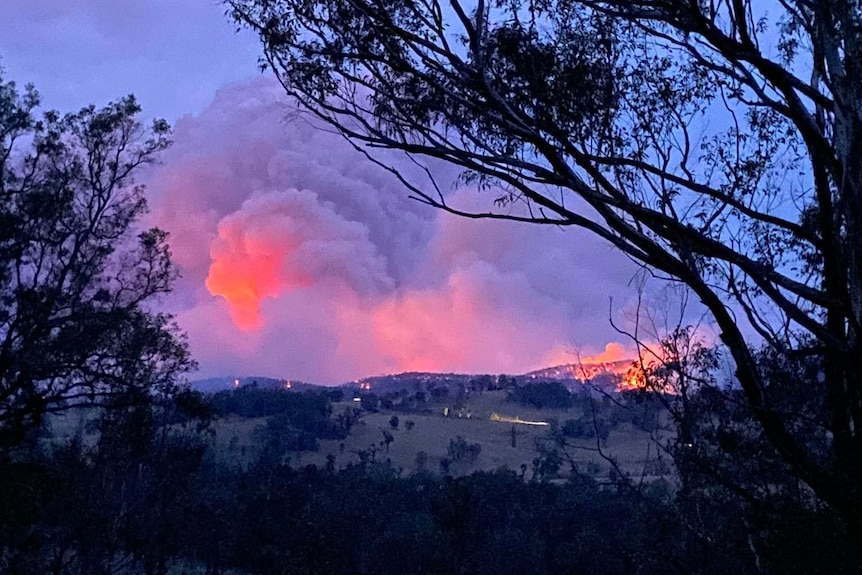 A fire burns on a bushy hill in the far distance.