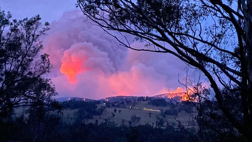 A fire burns on a bushy hill in the far distance.