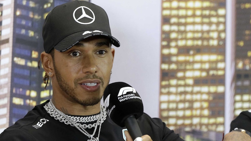 F1 driver Lewis Hamilton speaks into a microphone during a press conference.