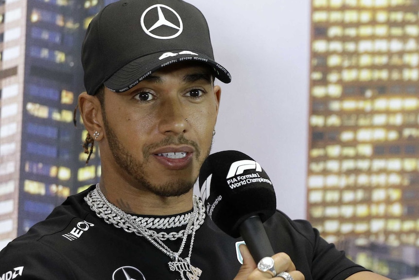 F1 driver Lewis Hamilton speaks into a microphone during a press conference.