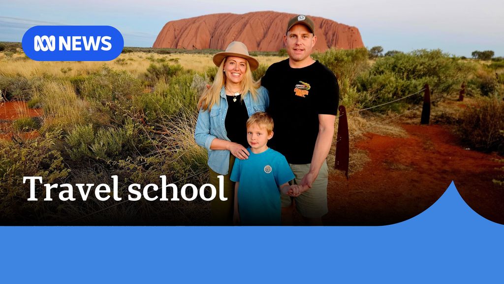 Travel school. Man, woman and boy standing in family group with Uluru as the backdrop. 