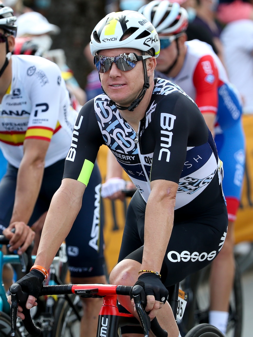 A male road cyclist wearing black and white sits on his bike