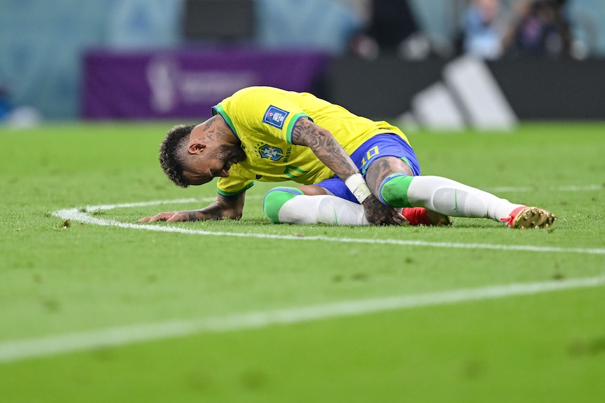 Neymar lies on the turf clutching his right ankle.