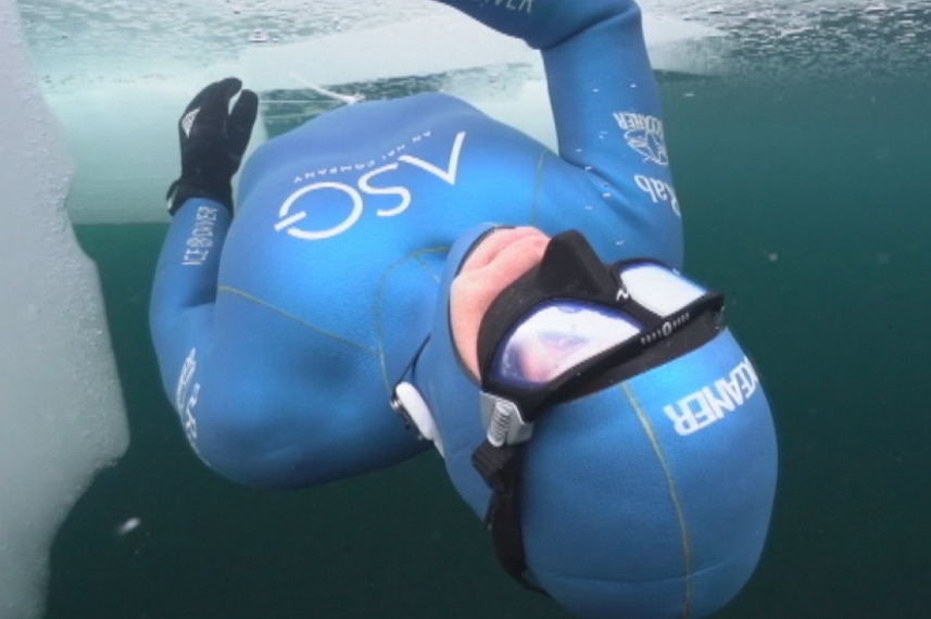 Ant Williams in a wetsuit diving beneath the ice