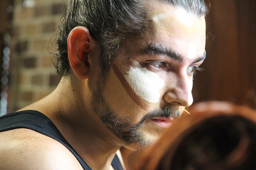 A young man applies theatrical makeup