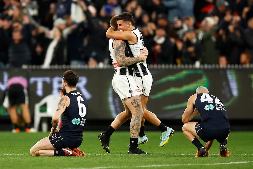 Two Collingwood AFL players embrace as they celebrate beating Carlton.