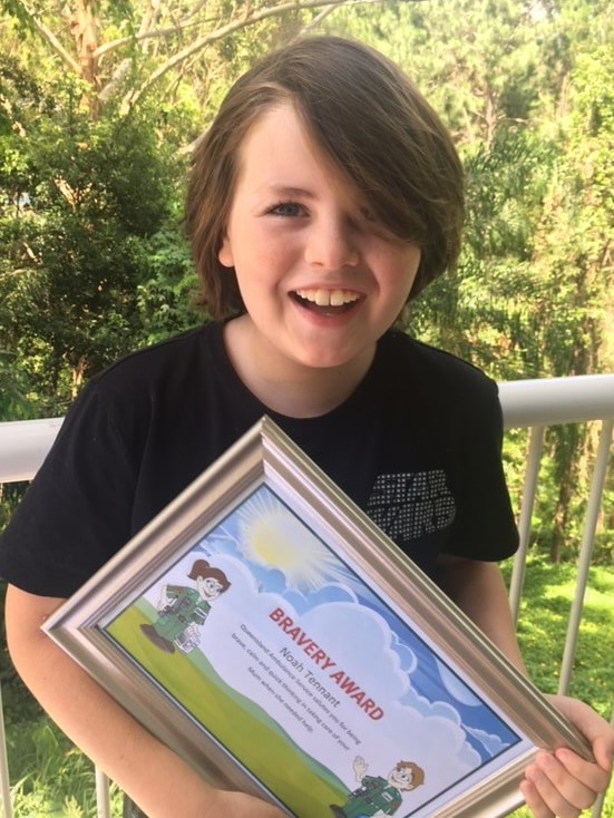 Young boy smiles as he holds bravery certificate