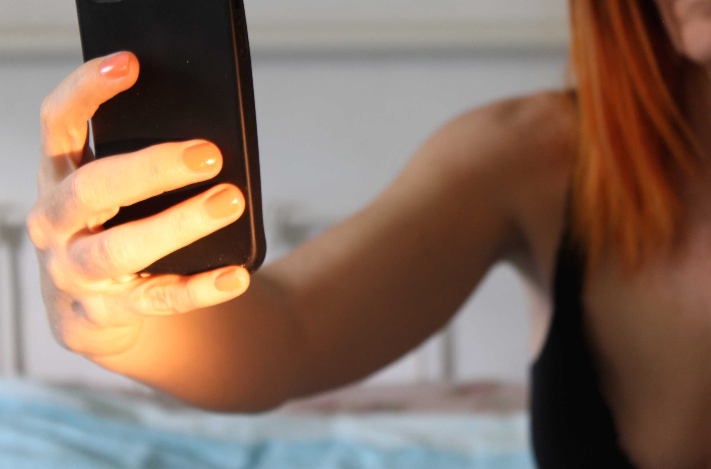 An unidentified woman holds as mobile photo up at arms-length to take a 'selfie'.