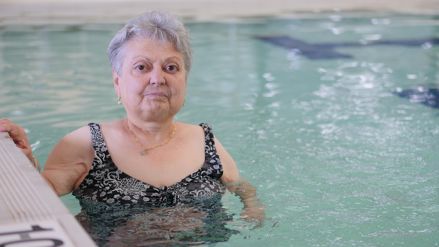 A woman in a pool holding on to the edge