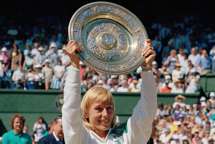 Martina Navratilova holds up a large silver trophy