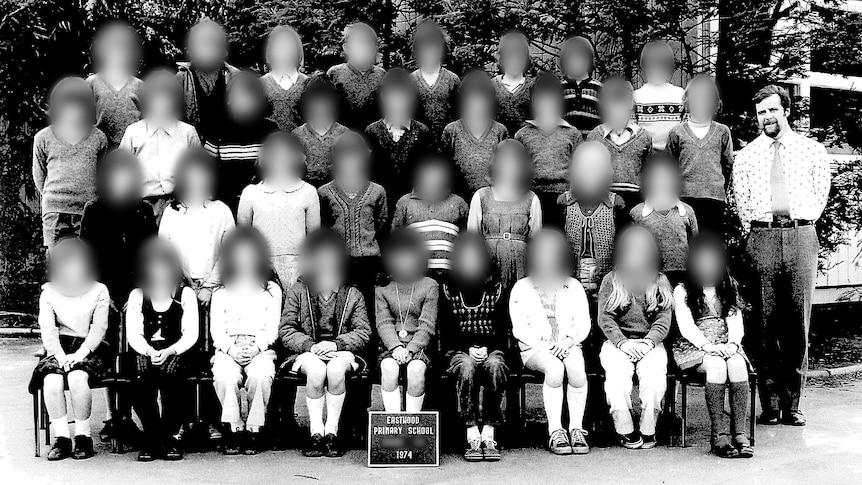 A black and white class photo with a male teacher and the faces of all the children blurred.