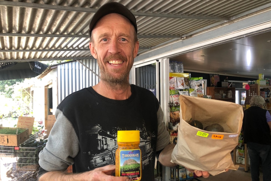 Neil Federer holds up fresh passionfruit and bottled passionfruit pulp.