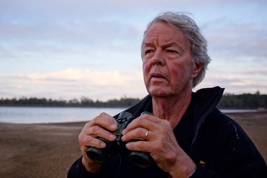 Ecologist Per Christensen looks into the distance with a pair of binoculars at the Talison lithium mine.