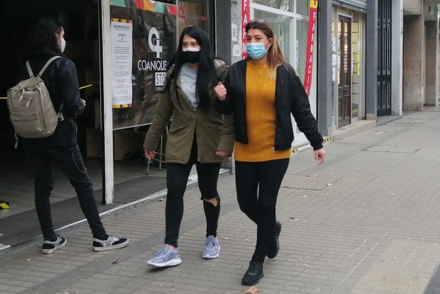 People walking in a street in Santiago wearing face masks.