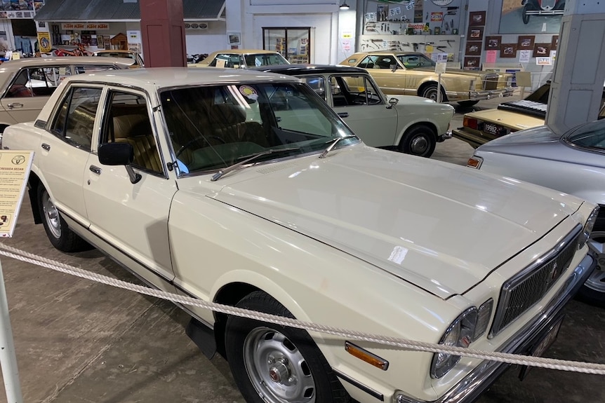 A white Toyota Cressida parked in a museum warehouse.