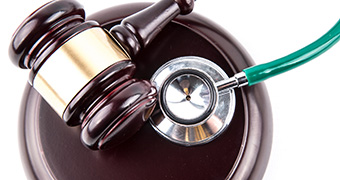 A gavel and a stethoscope on a white table.