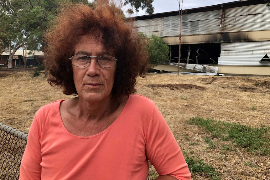 A person stands in front of a damaged building.