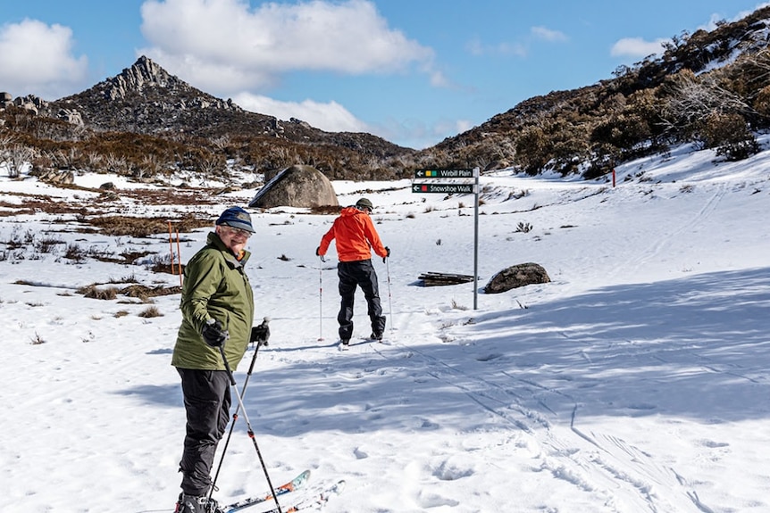 Two people stand on skis on a snowy plain.