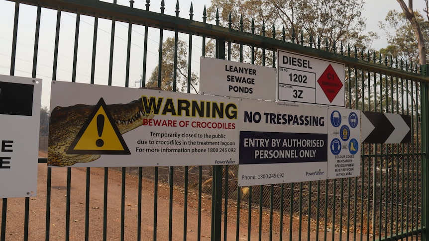 A warning sign warning about crocodiles can be seen on a bit, black gate.