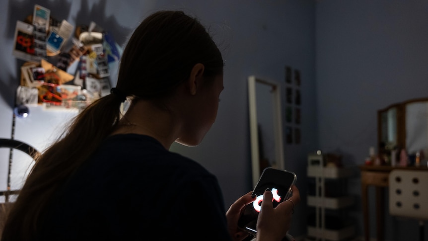 A teenager uses her mobile phone to access social media.