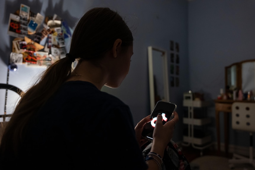 A teenager uses her mobile phone to access social media.