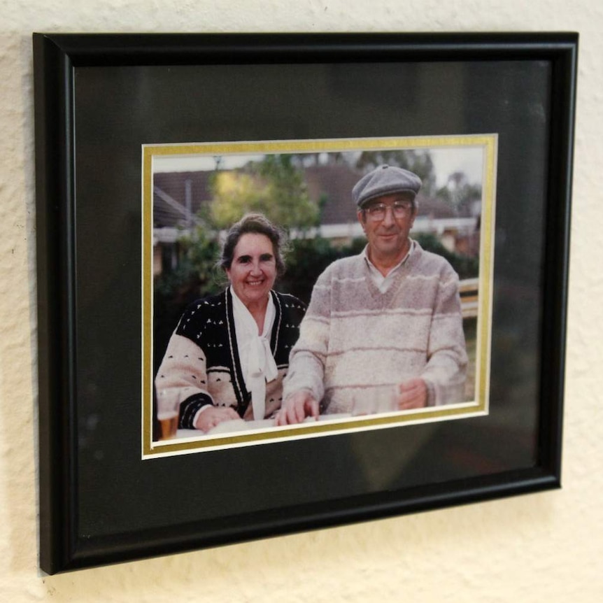 A framed photograph of Kali (left) and Stan (right) Paxinos in a suburban backyard.