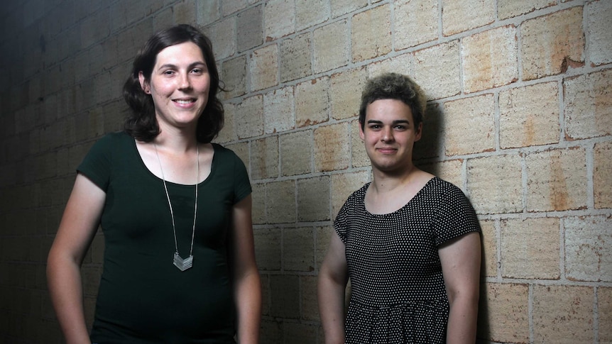 Chelsey Sanderson and Charlotte Tortorella stand next to a brick wall.