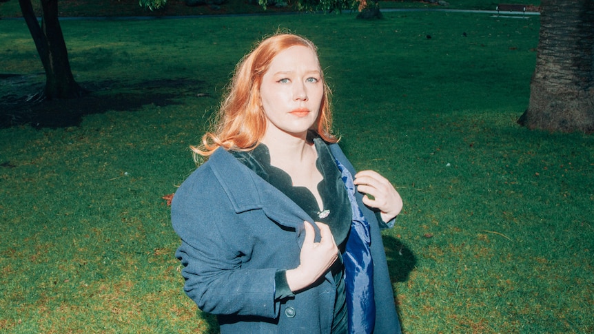 Julia Jacklin standing in a park wearing a navy winter pea coat