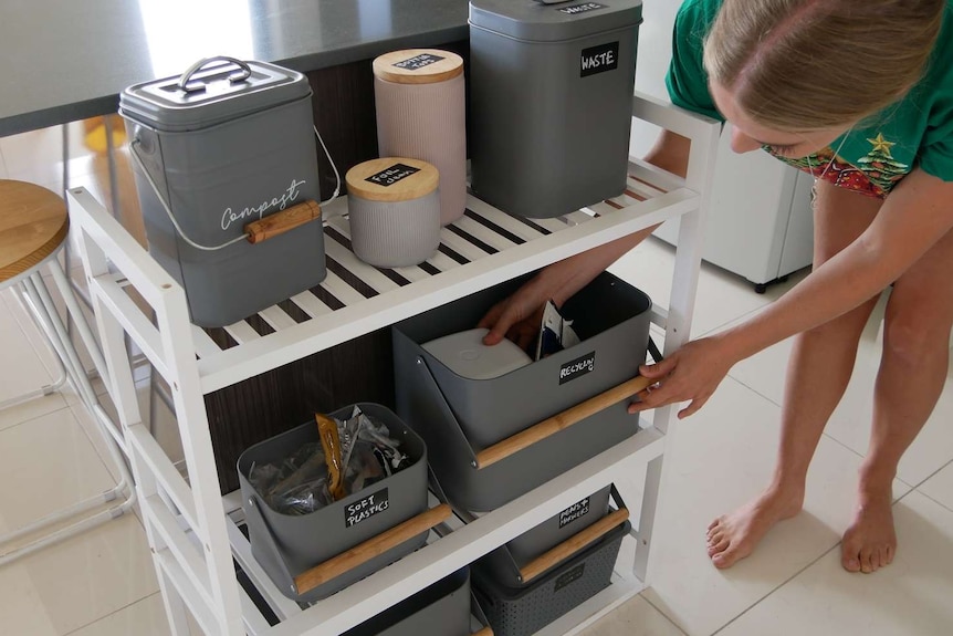 A woman stands over her homemade waste disposal system.