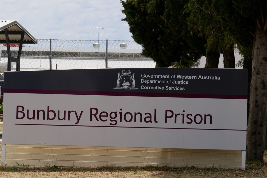 A sign that reads "Bunbury Regional Prison" stands in front of a building in the countryside.