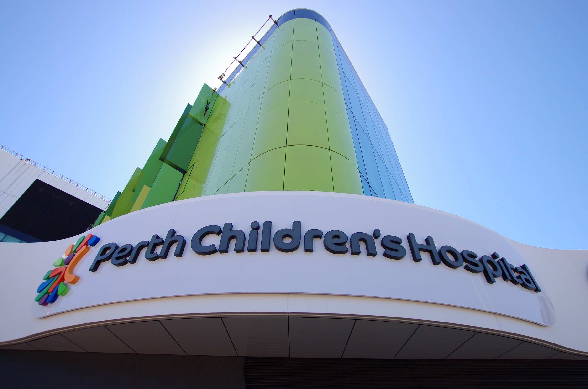 A shot from the ground of a Perth Children's Hospital sign and green building.