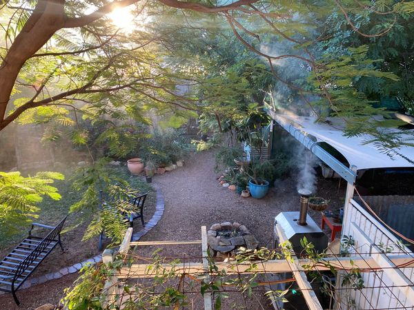 Lush green backyard with smoke rising from a pizza oven.