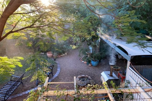 Lush green backyard with smoke rising from a pizza oven.