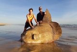 Two men stand behind a giant sunfish along the Coorong