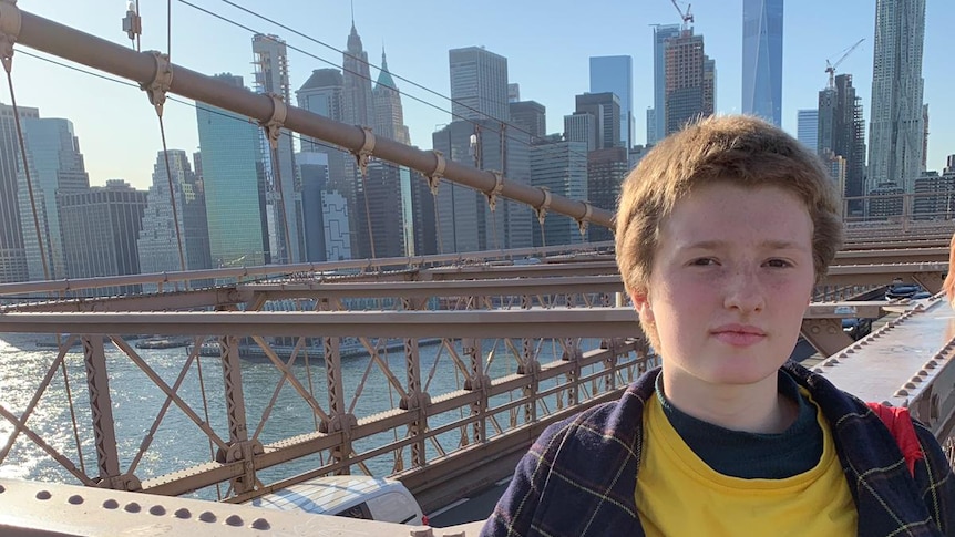 Harriet O'Shea Carre wears a yellow top under a check jacket with the New York skyline behind her.