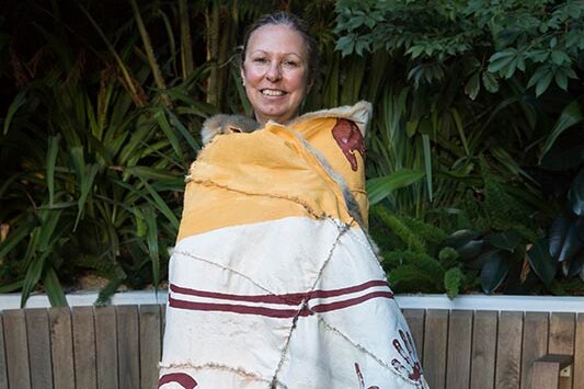 A woman wearing a possum skin cloak