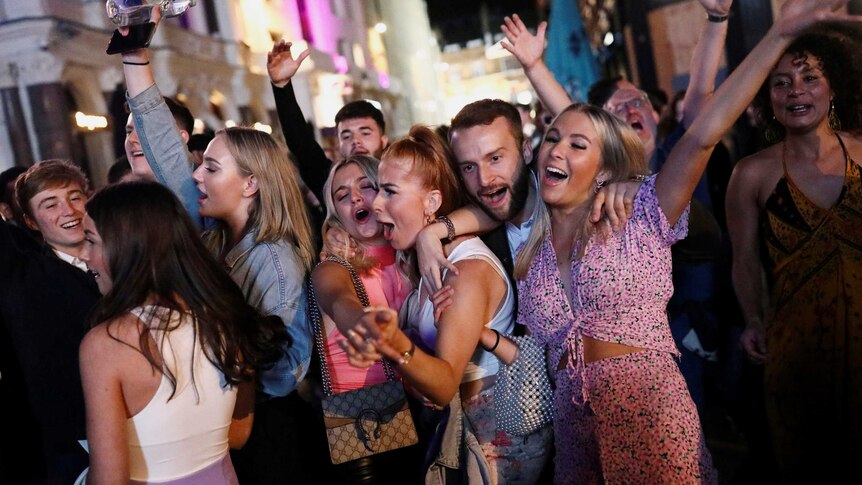 A group of young people dancing and hugging in the street at night