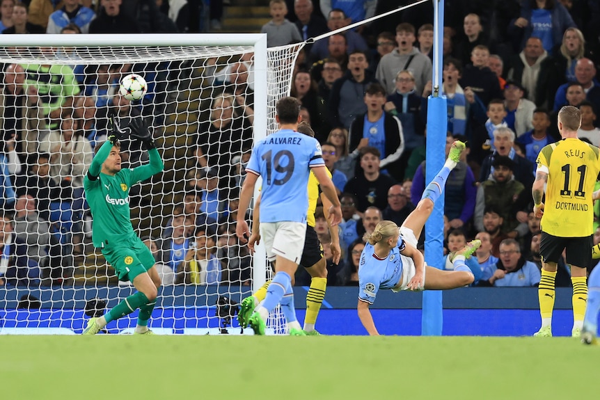 Erling Haaland's leaping kick sends a ball over the head of Borussia Dortmund goalkeeper Alexander Meyer.