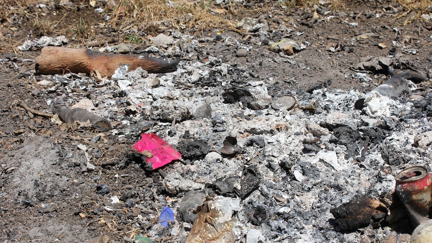 Photo shows burnt rubbish in a pile.