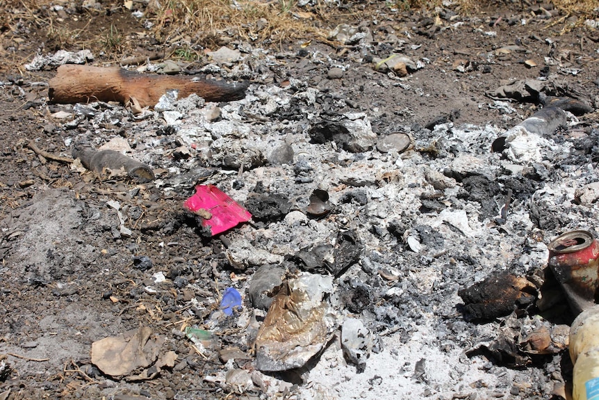Photo shows burnt rubbish in a pile.